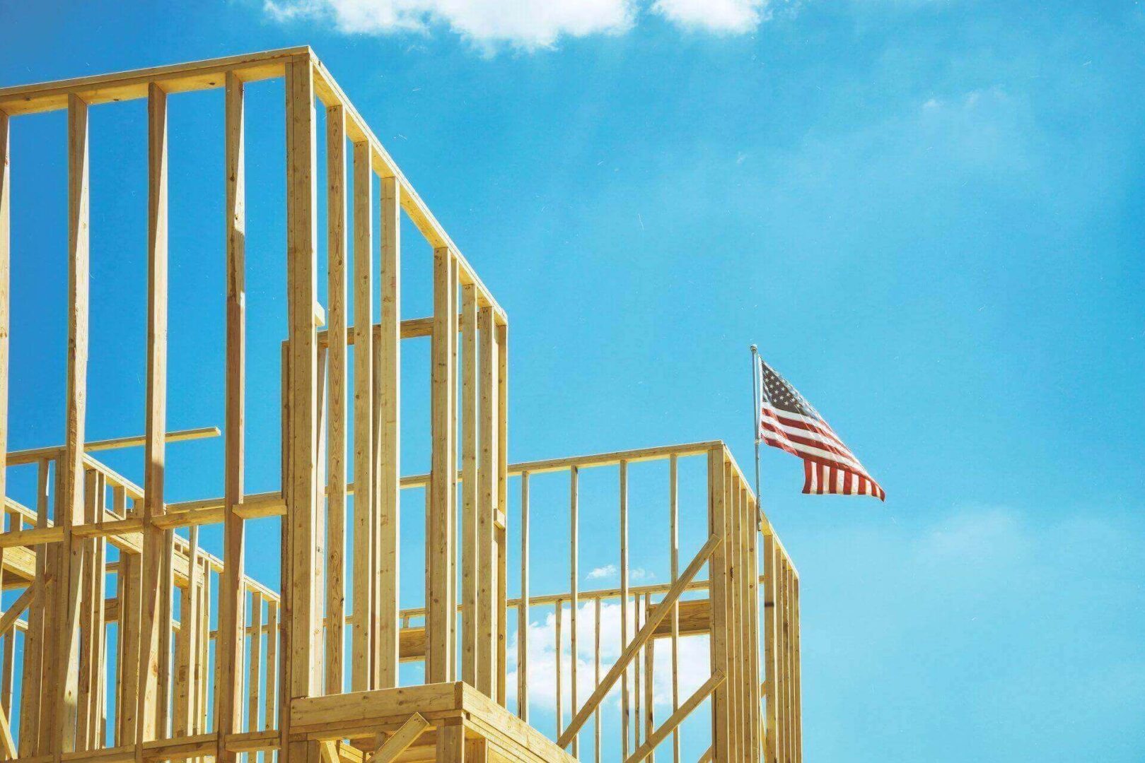 Wooden house frame with American flag, sky.